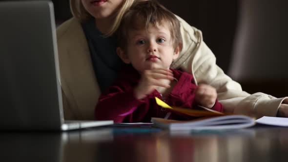 Little boy play with pencils while mother is working at home