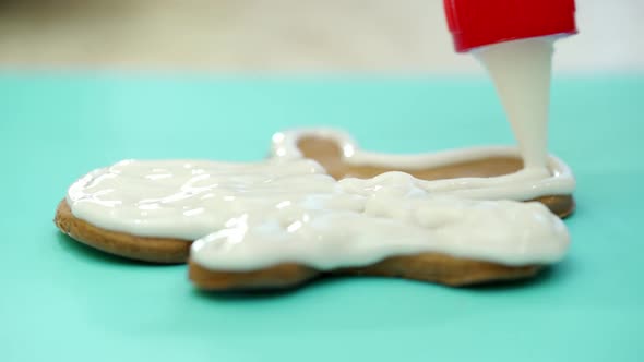 Close-up gingerbread cookie covering by white icing on the blue background. 