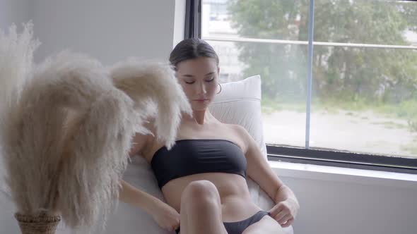 Model On Her Mid-Twenties Leaning On A Cozy White Couch Beside An Aesthetic Pampas Grass Decor. Slow