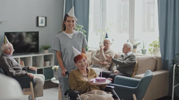 Portrait of Nurse and Senior Woman with Birthday Cake in Wheelchair