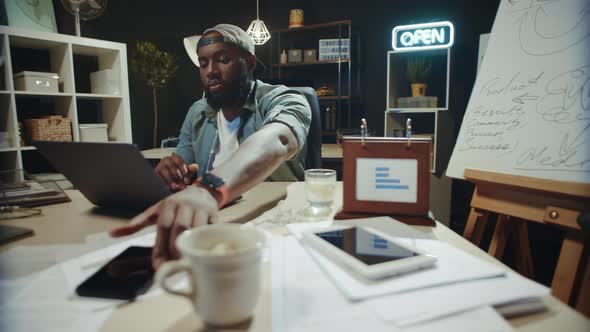 Overworked Afro Male Manager Typing on Computer in Hipster Office.