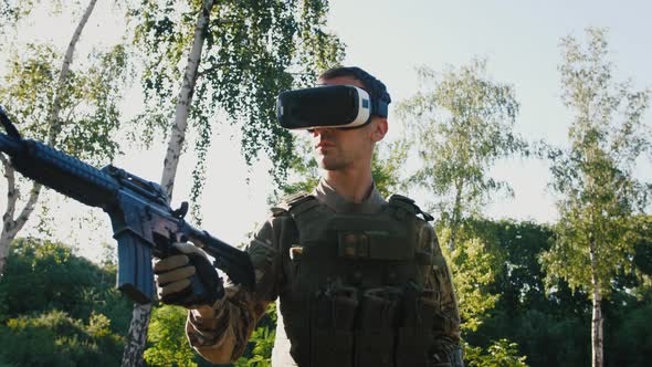 Soldier with Rifle Wearing Virtual Reality Glasses Outdoors