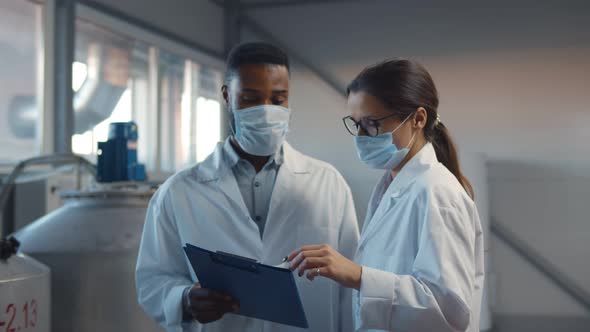 Two Technologists in Lab Coats and Mask at Factory Plant