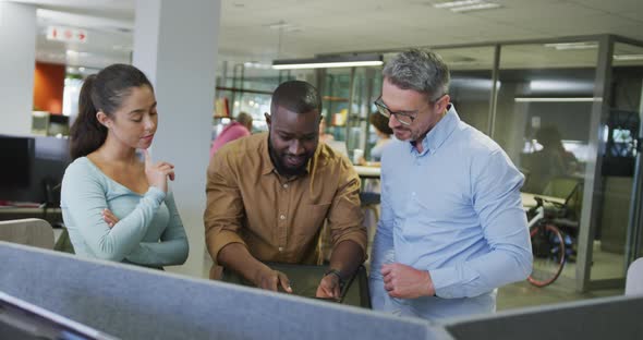 Diverse male and female business colleagues talking and using tablet