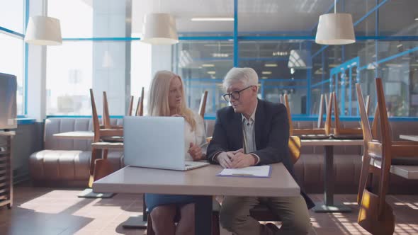 Mature Business Partner Work on Laptop in Closed Restaurant