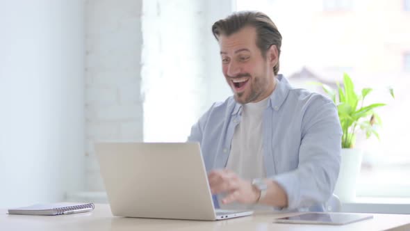 Young Man Celebrating Online Success in Office