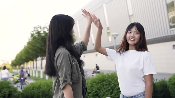 Young Asian Women Giving Each other High Five and Posing on Camera