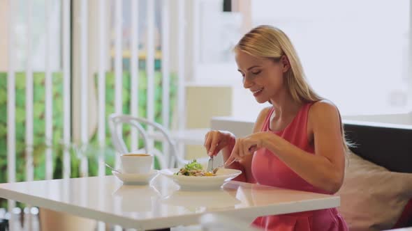 Woman Eating and Drinking Coffee at Restaurant 