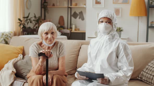 Portrait of Doctor in Protective Suit and Senior Woman at Home