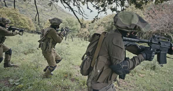 Squad of fully armed commando soldiers during combat in a forest scenery