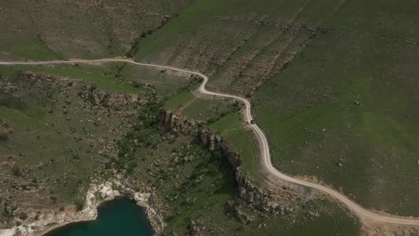 Aerial view of the mountain road through the green field.