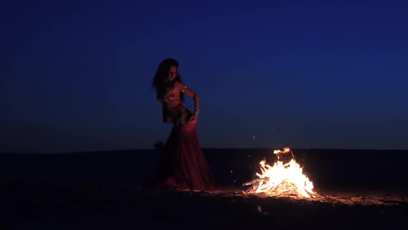 Evening a Girl in the Sand Dancing Belly Dancing Near a Bright Campfire