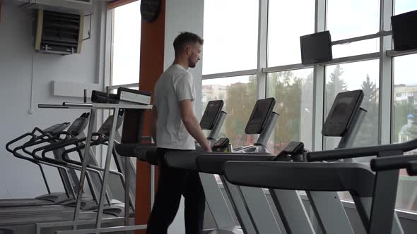 Young Athletic Man Jogging on Treadmill in Sport Gym Before Training