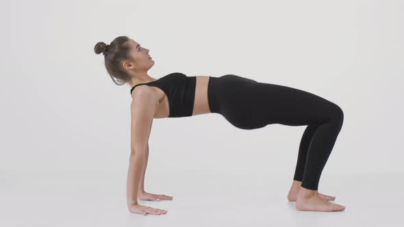 Young Active Lady Practicing Yoga Over White Studio Background Swinging Forward and Backward on Her