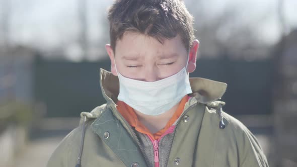 Close-up of Cute Brunette Caucasian Boy in Protective Face Mask Sneezing. Little Brown-eyed Child