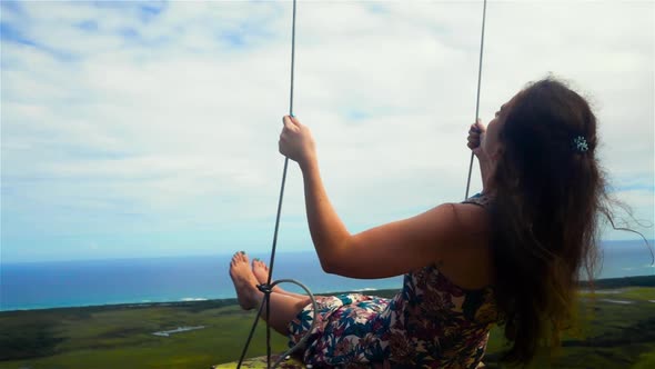 Woman on a Swing and a Blue Sky with Ocean and Mountain