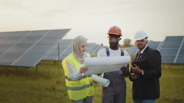 Group of Multi Ethnic People in Safety Helmet Standing Among Solar Farm and