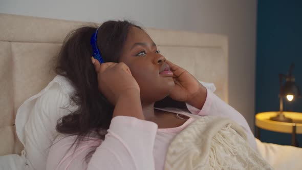 Female in Headphones Resting on Bed at Bedtime