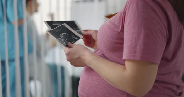 Cropped Shot of Pregnant Woman Touching Belly and Holding Sonogram Picture