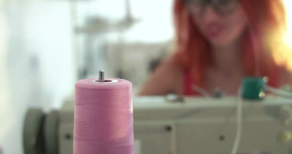 Dressmaker Looks at the Unwinding of the Spool of Thread While Sewing
