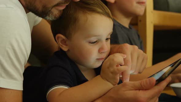 Side view of caucasian father and children using digital tablet in a comfortable home 4k