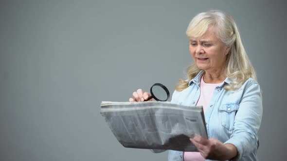 Elderly Lady Trying to Read Newspaper With Magnifying Glass, Poor Vision Problem