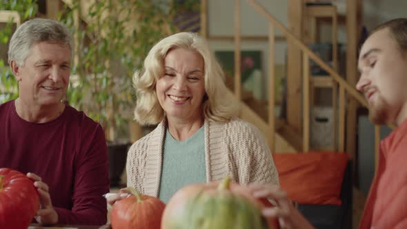 Grandmother and Old Man Discussing Pumpkin with Grandson for Halloween