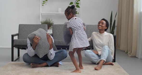 Overjoyed Young Afro American Family Parents with Little Child Girl Feel Playful Engaged in Pillow