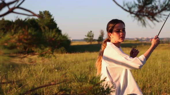 Swords Training  Young Woman Waving with a Sword on Nature at Early Evening