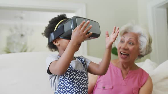 Happy african american grandmother with granddaughter using vr headset in living room