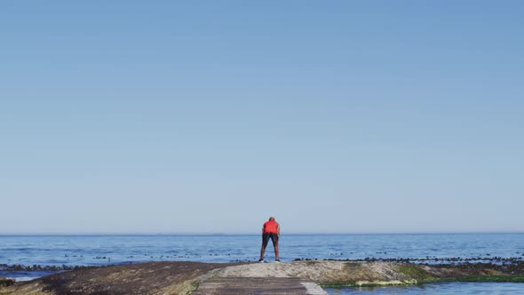 Senior african american man exercising raising hands by the sea