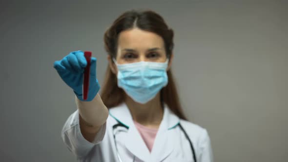 Researcher in Protective Mask Showing Tube With Blood Samples Epidemics