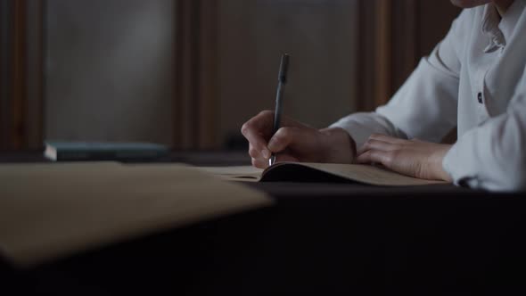 Closeup of female hand making notes, writing letter in personal diary with books.  Library Education