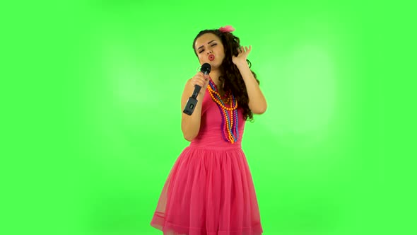 Attractive Girl Sings Into a Microphone and Moves To the Beat of Music. Green Screen