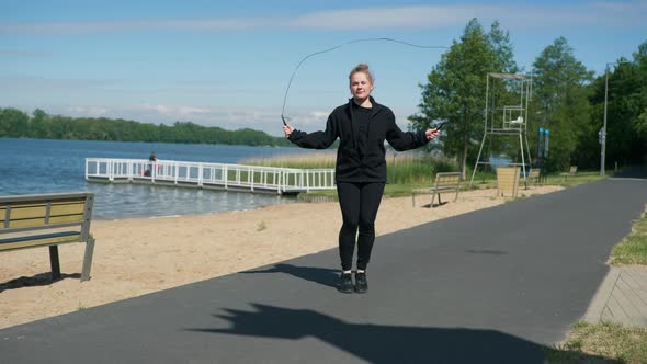 Young Girl Jumping Rope on the Embankment on a Sunny Day