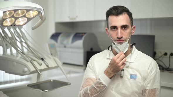 Portrait of a young dentist who takes off the mask and looks at the camera