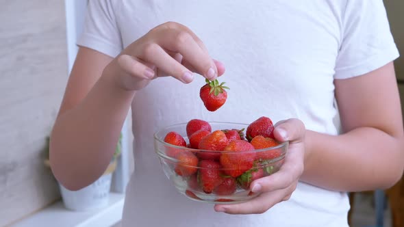 Child Holding in Hands Full Glass Bowl Red a Strawberry in Sunlight in Room