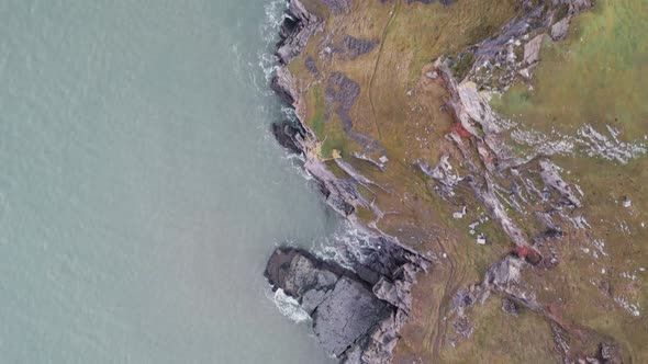 AERIAL: Top down fly along grass covered coastal cliffs, Rhossili Gower, 4k Drone