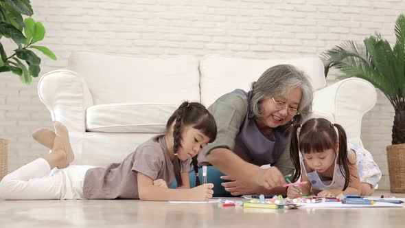 Elderly grandmother with two Asian granddaughter's Play wooden toys together in the living room