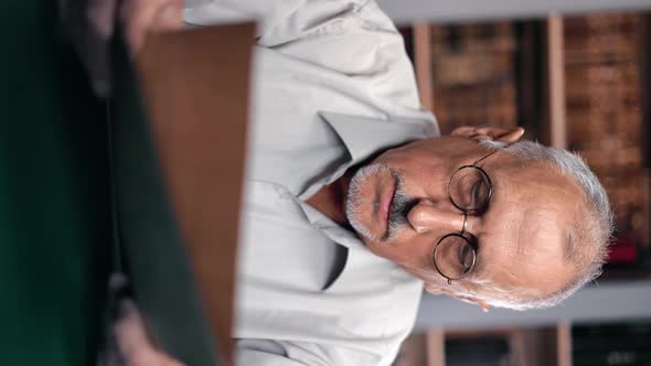 VERTICAL VIDEO POV Pensive Elderly Man Reading Paper Document Tax Payment Retirement Bill at Library