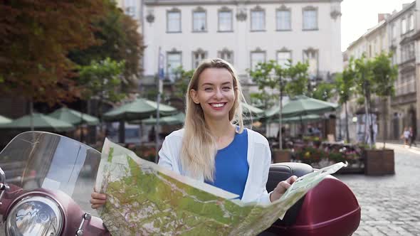 Woman Holding Tourist Map Sitting on the Perfect Scooter Near Beutiful Architecture