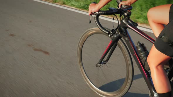 Legs of cyclist and bike wheel rotation, close up.