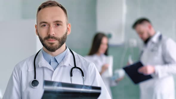 Caucasian Male Doctor with Beard and Stethoscope in White Lab Coat Holding Xray Snapshot