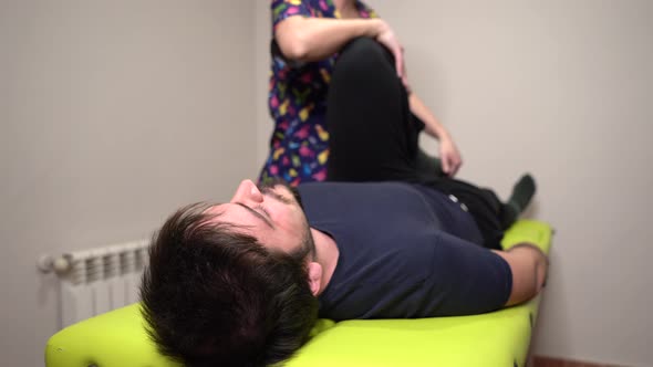 physiotherapist performing leg stretch exercise with patient on stretcher