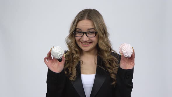 Hesitated Woman Holding Two Marshamallow and Wants To Eat It on Gray Background