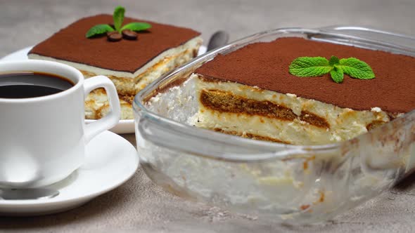 Traditional Italian Tiramisu dessert in glass baking dish and portion on grey concrete background