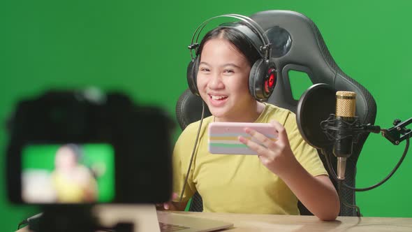 Kid Girl Holding Mobile Phone And Read Comment In Laptop Then Talking To Camera While Live Stream alt