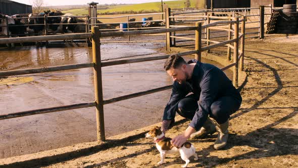 Cattle farmer petting dog near barn