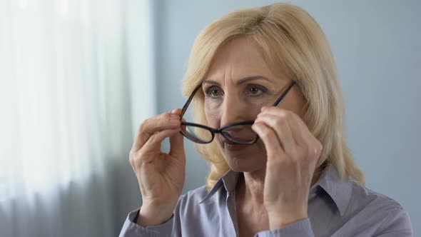 Senior Businesswoman Putting on Eyeglasses and Smiling in Front of Mirror Health