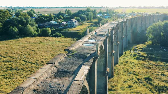 Athletic Lady is Crossing an Ancient Bridge